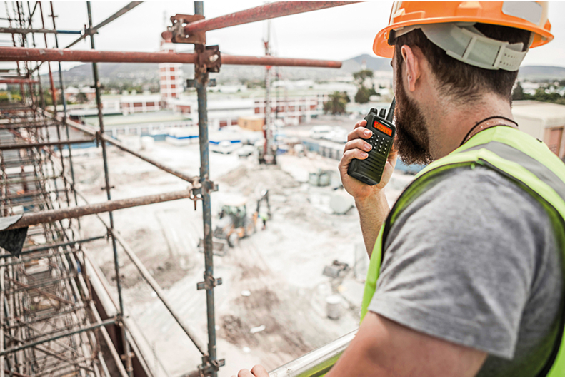 Construction worker using a two-way radio on a building site